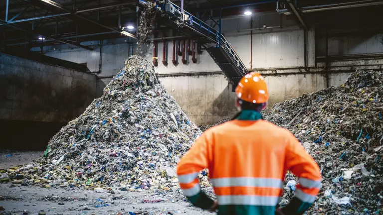 A recycling factory worker in an orange reflective vest
